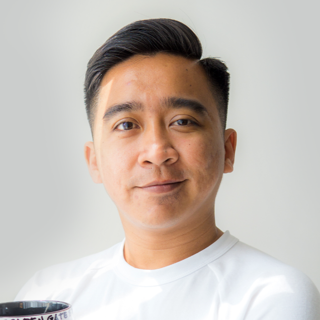 An image of a smiling fine looking man in a white t-shirt against a white wall